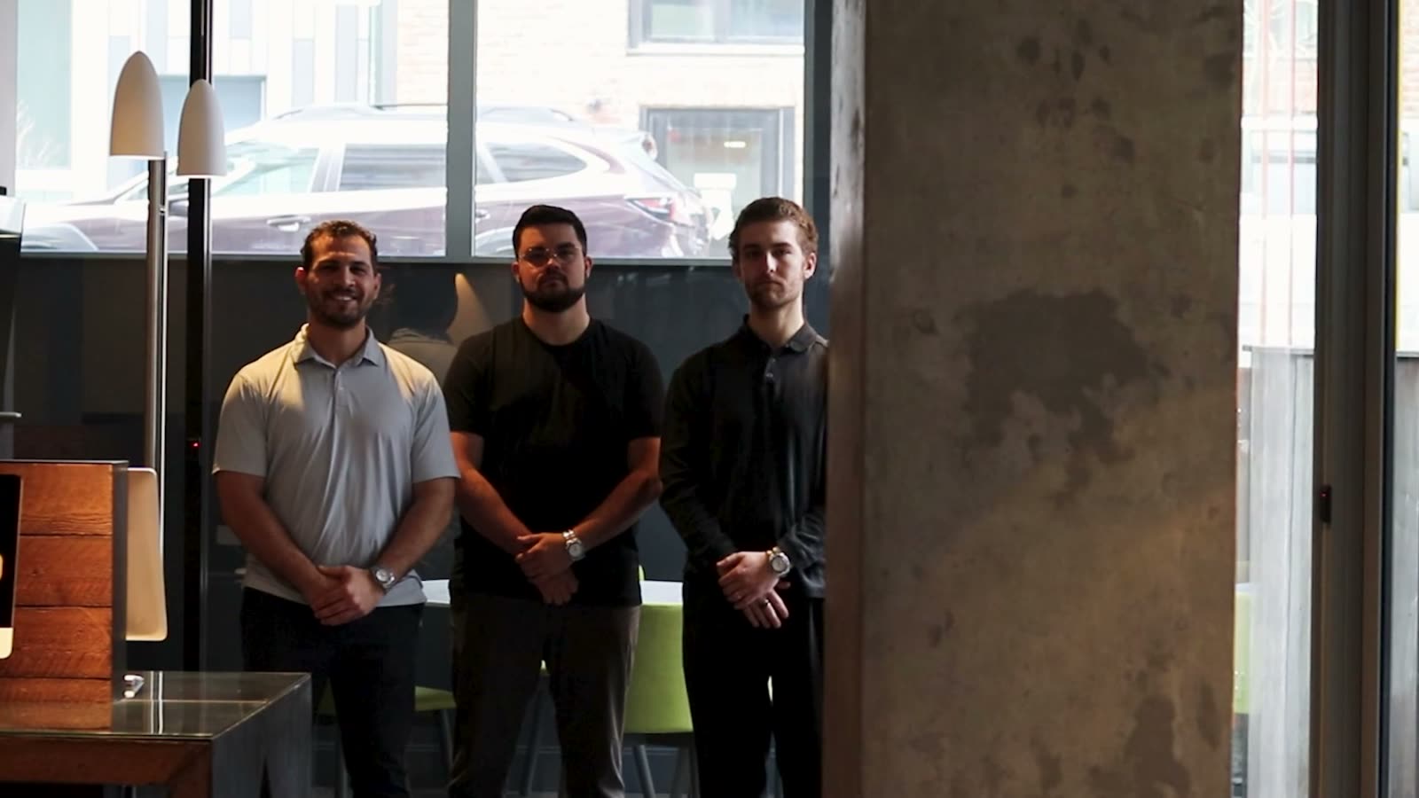 A frame from the film: the three founders standing together in the office.